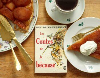 a slice of tarte tatin with crème fraîche and a volume of Maupassant's novellas