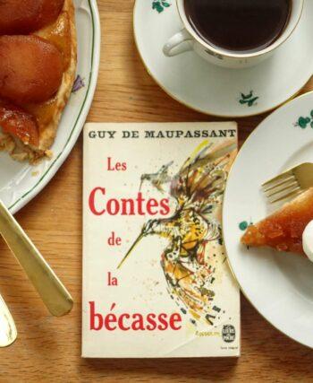 a slice of tarte tatin with crème fraîche and a volume of Maupassant's novellas
