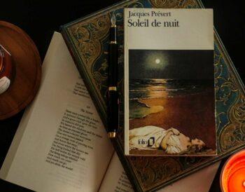 flat lay of a poetry book by French classic Jacques Prévert on a table with two candles and an open book of poems