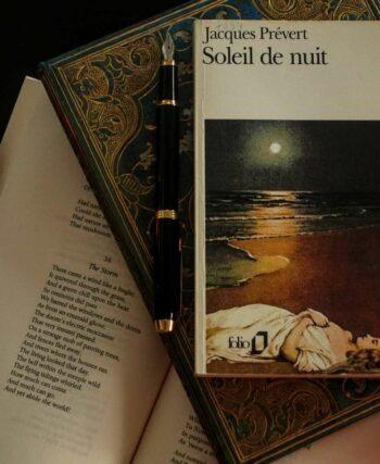 flat lay of a poetry book by French classic Jacques Prévert on a table with two candles and an open book of poems
