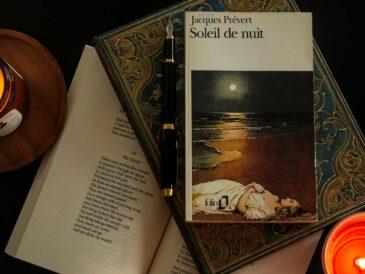 flat lay of a poetry book by French classic Jacques Prévert on a table with two candles and an open book of poems