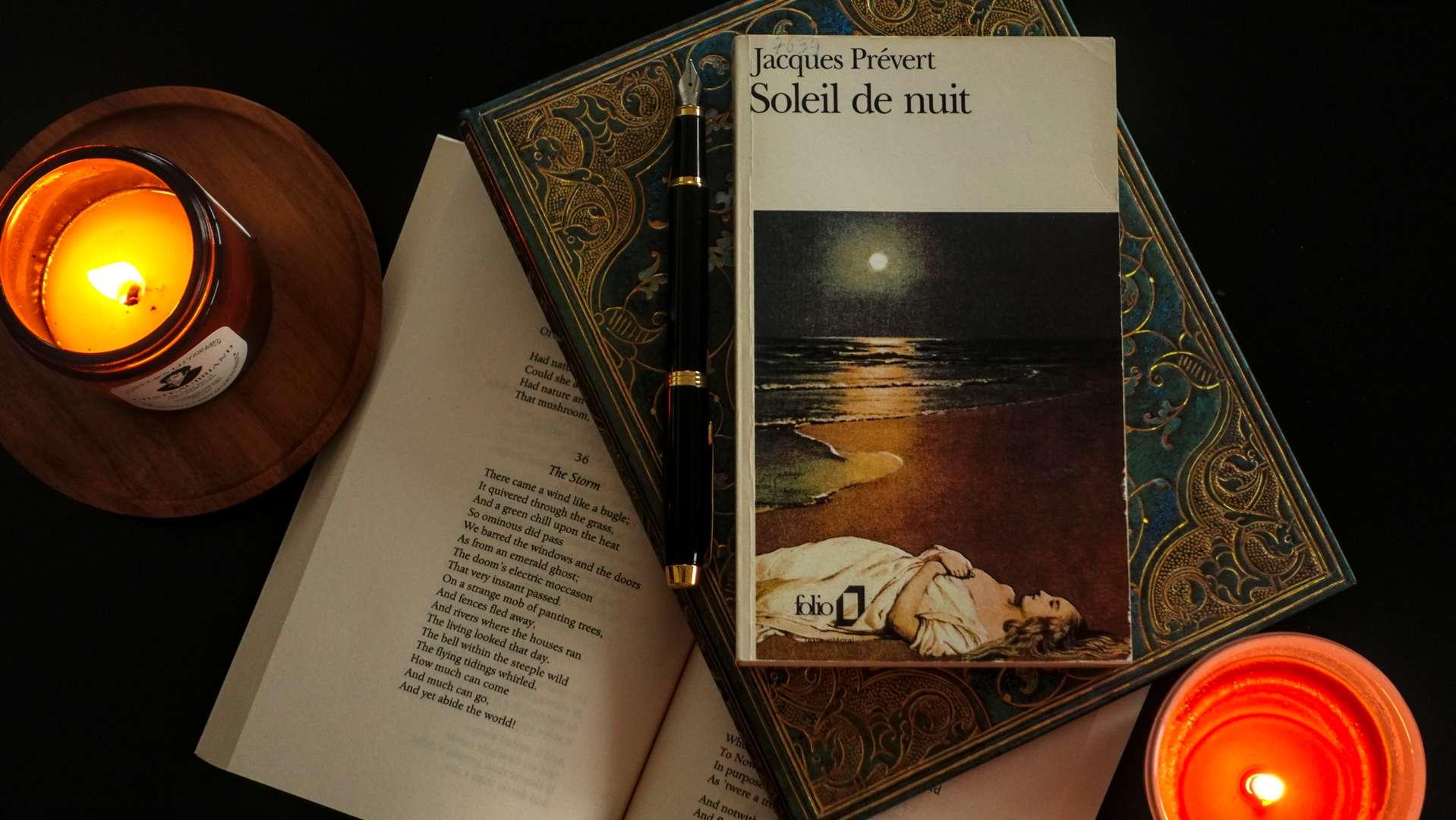 flat lay of a poetry book by French classic Jacques Prévert on a table with two candles and an open book of poems