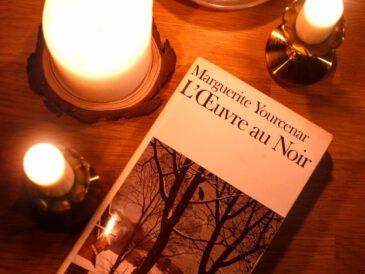 a copy of Marguerite Yourcenar's novel L'oeuvre au noir or The Abyss surounded by candles