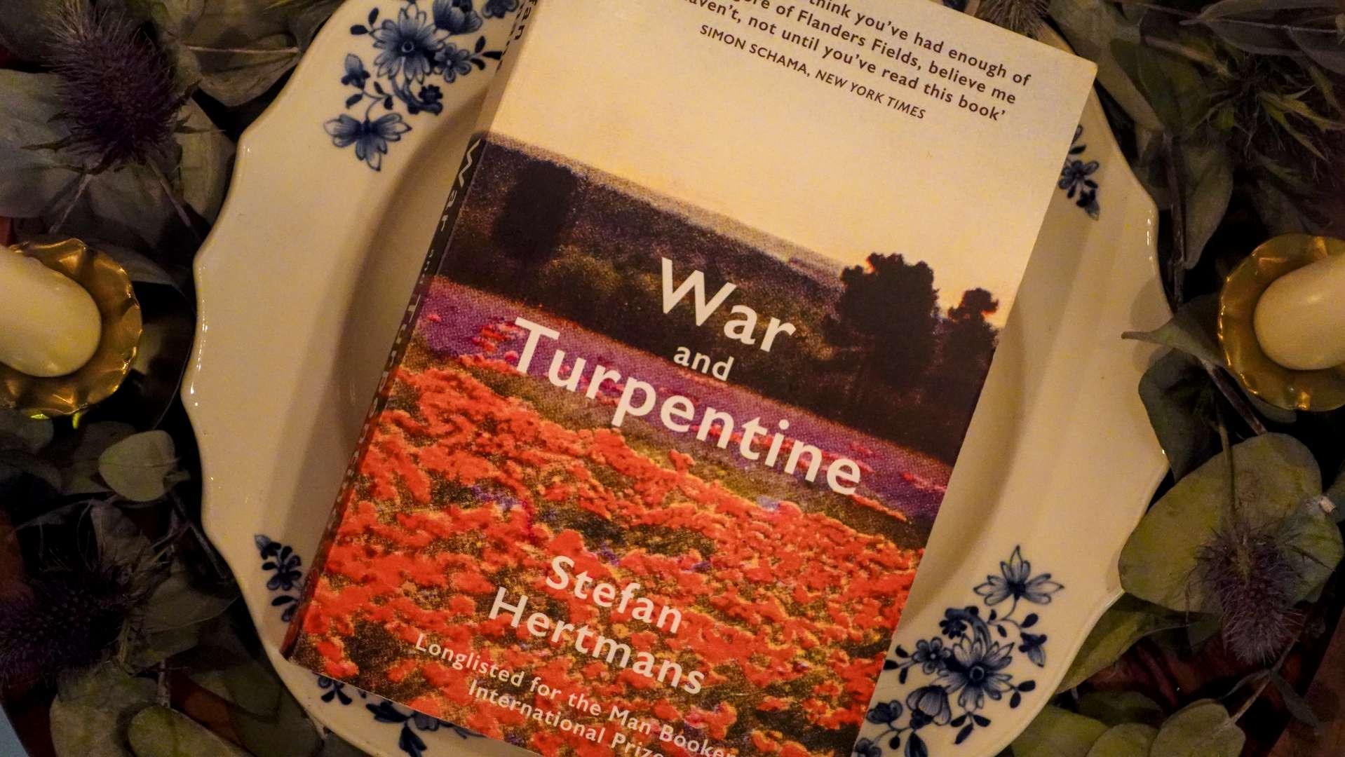 A copy of War and Turpentine by Stefan Hertmans placed on a Belgian porcelain plate, symbolizing the link between art and memory.