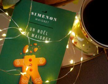 A copy of Maigret’s Christmas by Georges Simenon on a dark wood table with a cup of coffee.