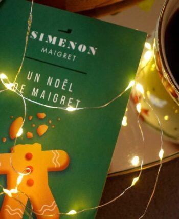 A copy of Maigret’s Christmas by Georges Simenon on a dark wood table with a cup of coffee.