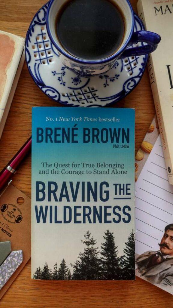 A close-up shot of the book cover for 'Braving the Wilderness' by Brené Brown, showing the wilderness-themed design.