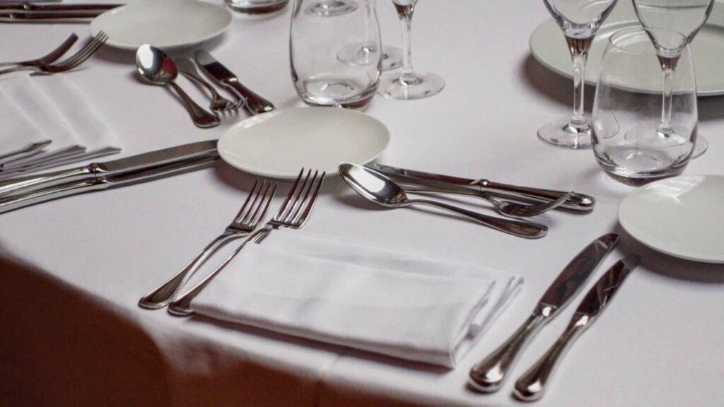 A formal dining table setting featuring elegant silverware, crystal glassware, and porcelain plates illustrating traditional table manners.
