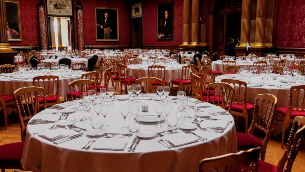 A grand reception room prepared for an official state dinner with ornate architecture, chandeliers, and sophisticated decor for high society events.