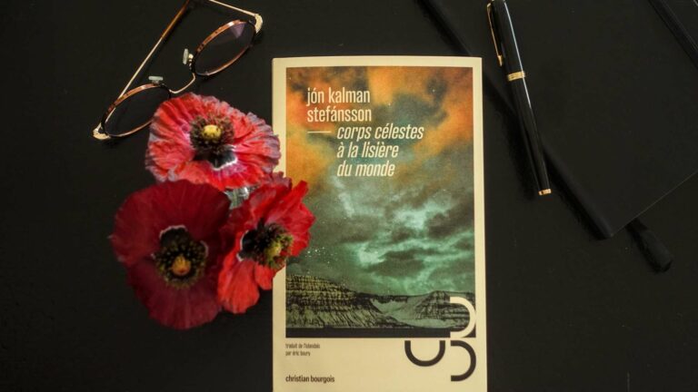 Front cover of Jón Kalman Stefánsson’s novel "Corps célestes à la lisière du monde" on a black table next to a pair of glasses and red poppy flowers.