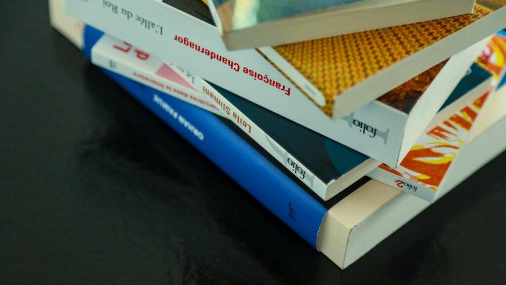 A stack of unfinished books on a black table